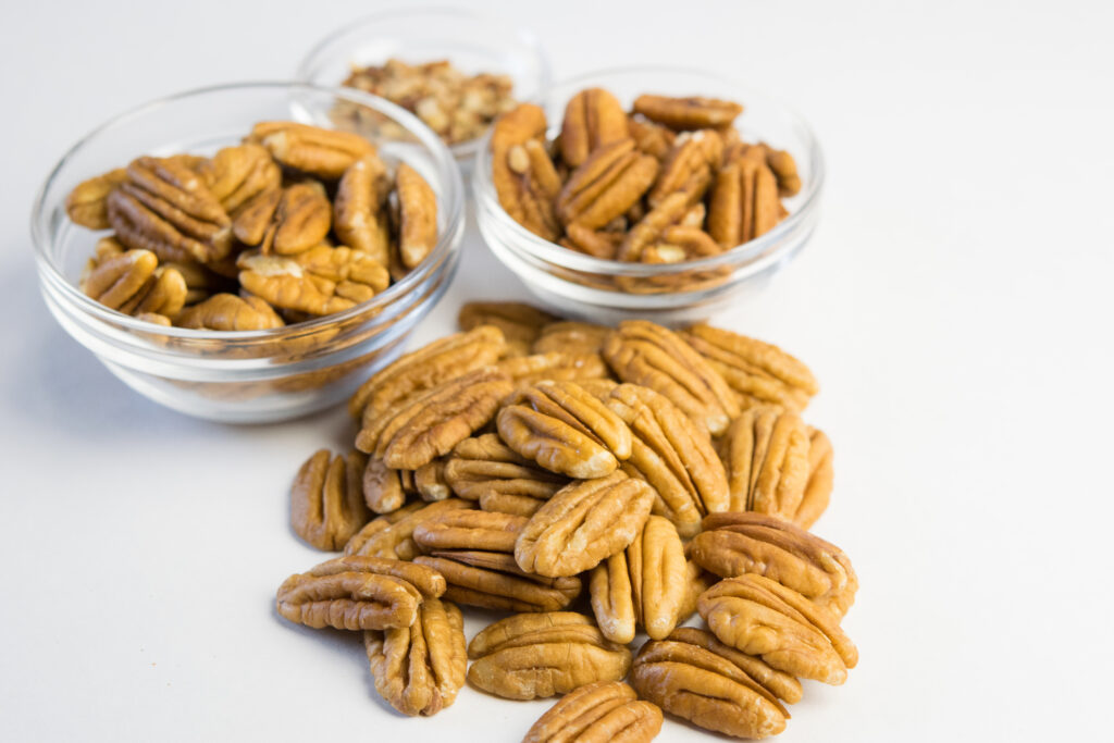 Pile of pecans next to some small dishes of pecans