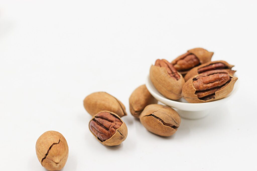 Pecans laying next to a small dish of pecans
